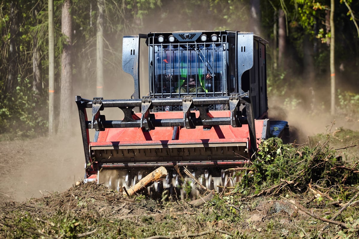 Forestry mulcher cleaning vegetation and biomass in a wooded area